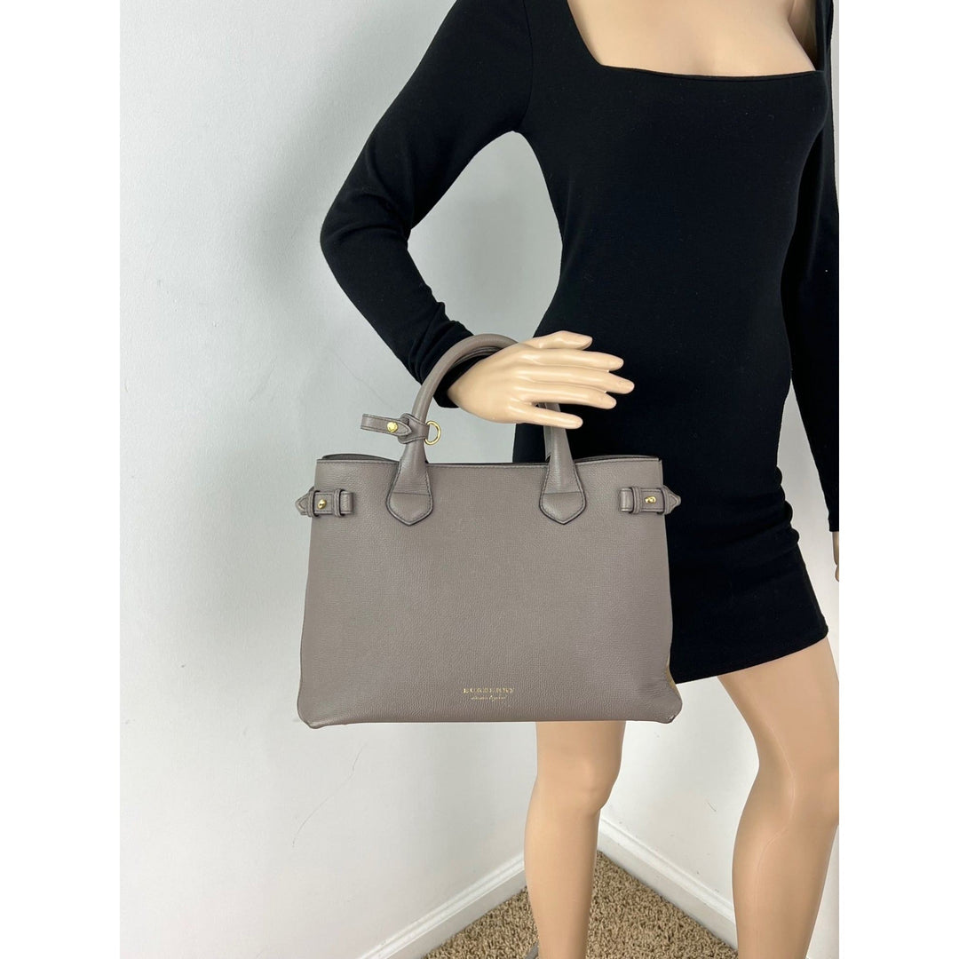 Mannequin wearing a black outfit holding a gray handbag against a white background