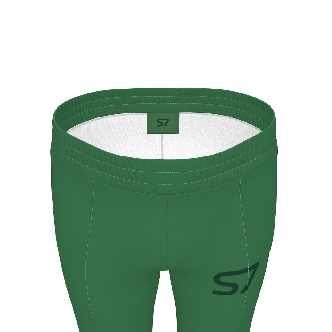 S7 Heritage Green tracksuit pants with a dark forest-green upper-thigh logo and matching stripes down the outer legs.