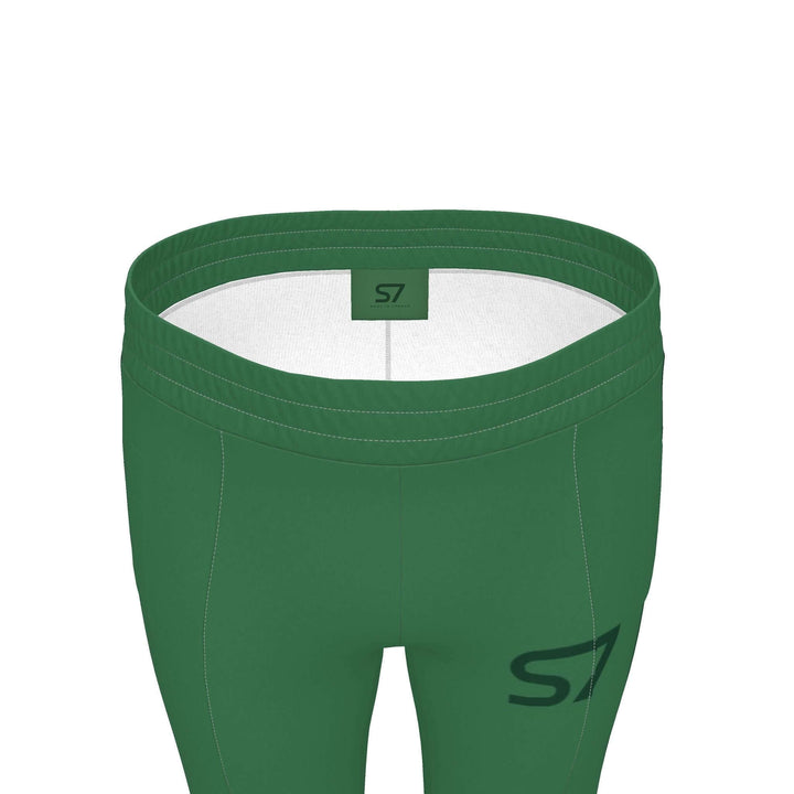 S7 Heritage Green tracksuit pants with a dark forest-green upper-thigh logo and matching stripes down the outer legs.