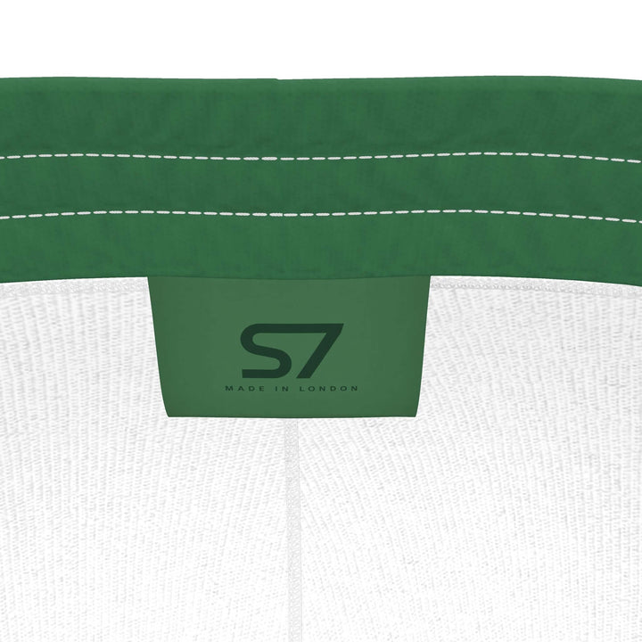 S7 Heritage Green tracksuit pants with a dark forest-green upper-thigh logo and matching stripes down the outer legs.