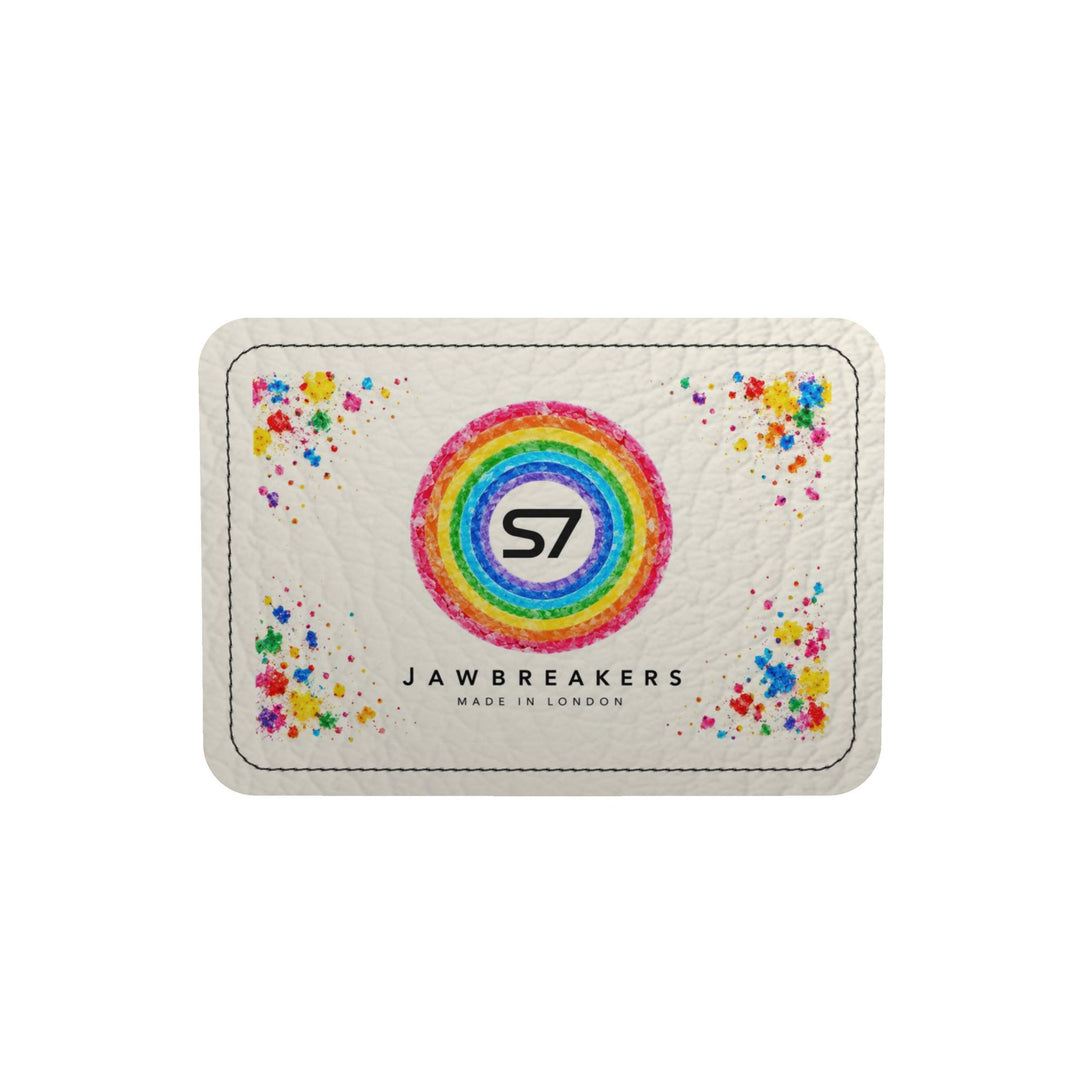 A square white textured card or patch with rounded corners, featuring a colorful rainbow ring with the black &