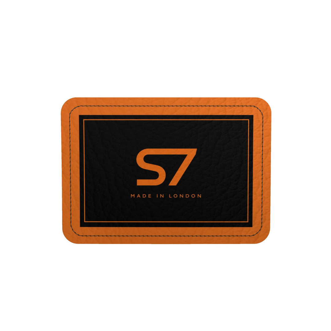 S7 Solar Noir orange leather duffle bag with scattered black five-point stars, a centered black S7 monogram and black handles and end panels.
