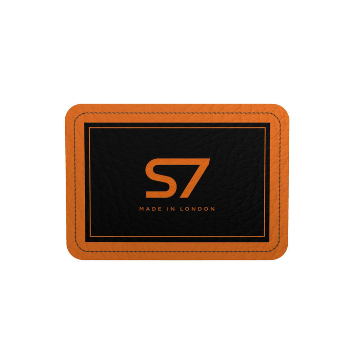 S7 Solar Noir orange leather duffle bag with scattered black five-point stars, a centered black S7 monogram and black handles and end panels.