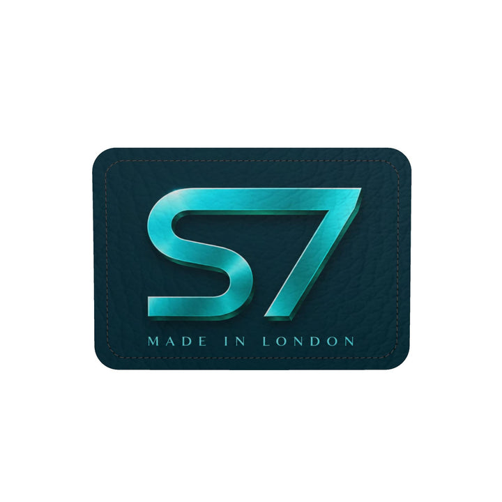 S7 Electric Lagoon bag featuring dimensional turquoise monograms, midnight teal side panels, and nickel-tone hardware.