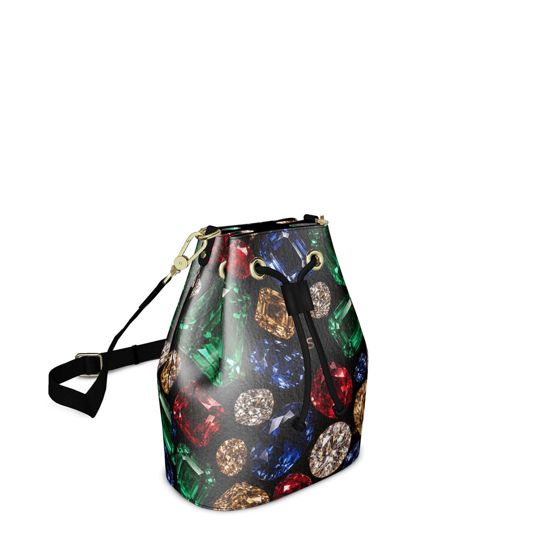 S7 Jewel Vault leather bucket bag with colorful gemstone print on black, a subtle rose-gold monogram, black shoulder strap, and gold-tone hardware.