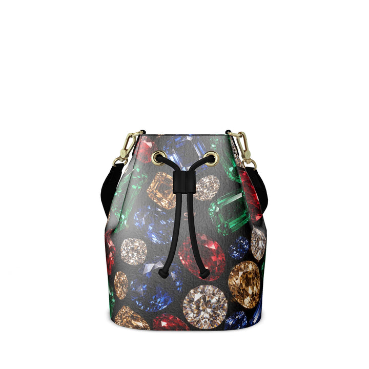 S7 Jewel Vault leather bucket bag with colorful gemstone print on black, a subtle rose-gold monogram, black shoulder strap, and gold-tone hardware.