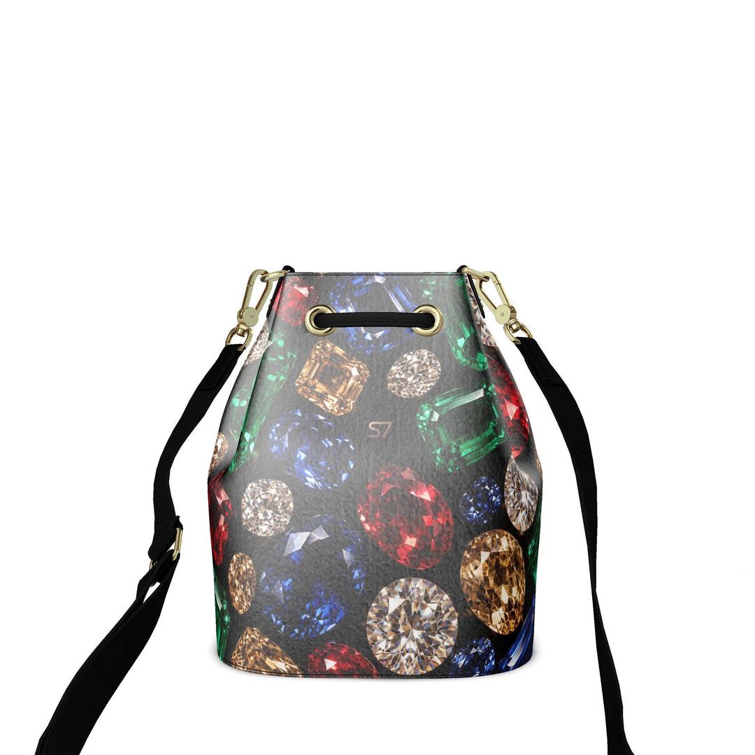S7 Jewel Vault leather bucket bag with colorful gemstone print on black, a subtle rose-gold monogram, black shoulder strap, and gold-tone hardware.
