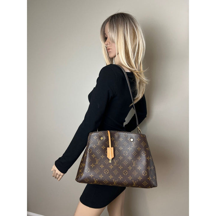 Woman carrying a brown patterned handbag against a plain background