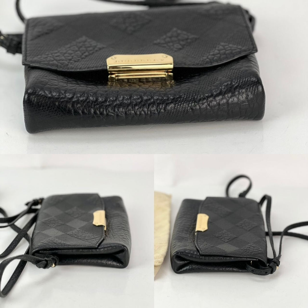 Black textured handbag with gold clasp on a white background