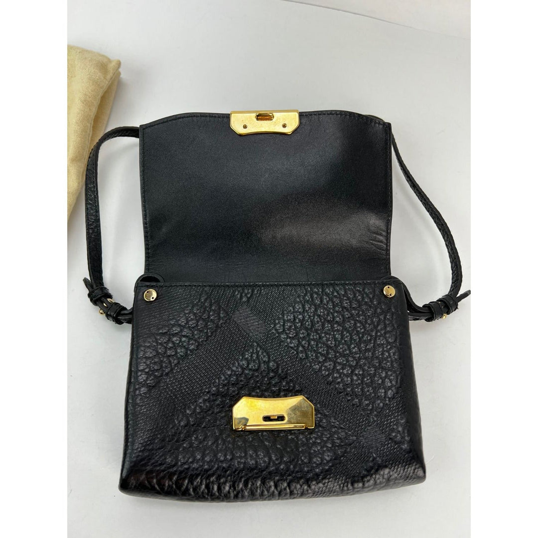 Black textured handbag with gold accents on a light gray background