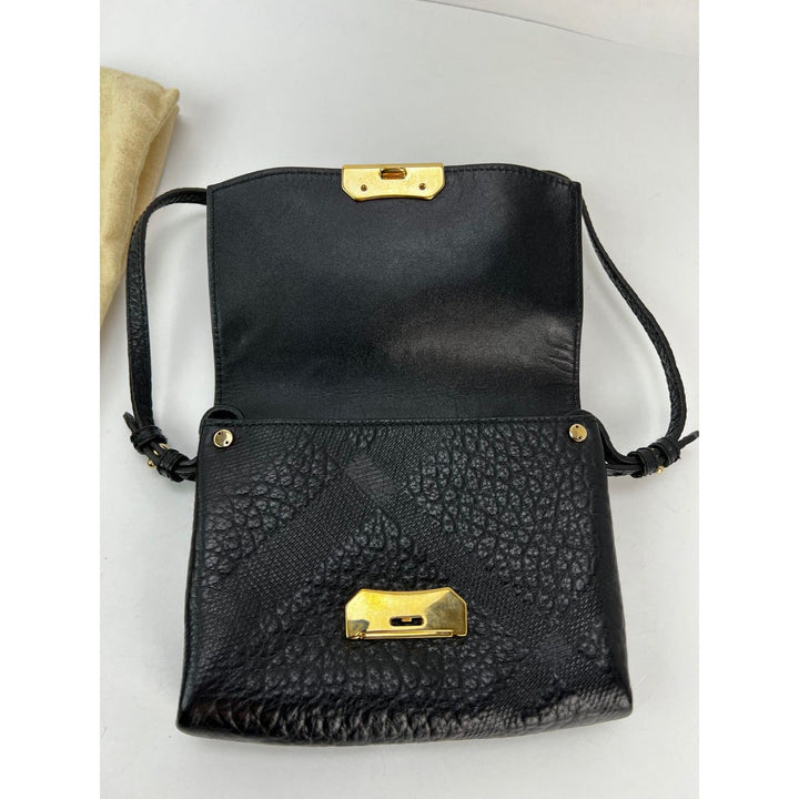 Black textured handbag with gold accents on a light gray background