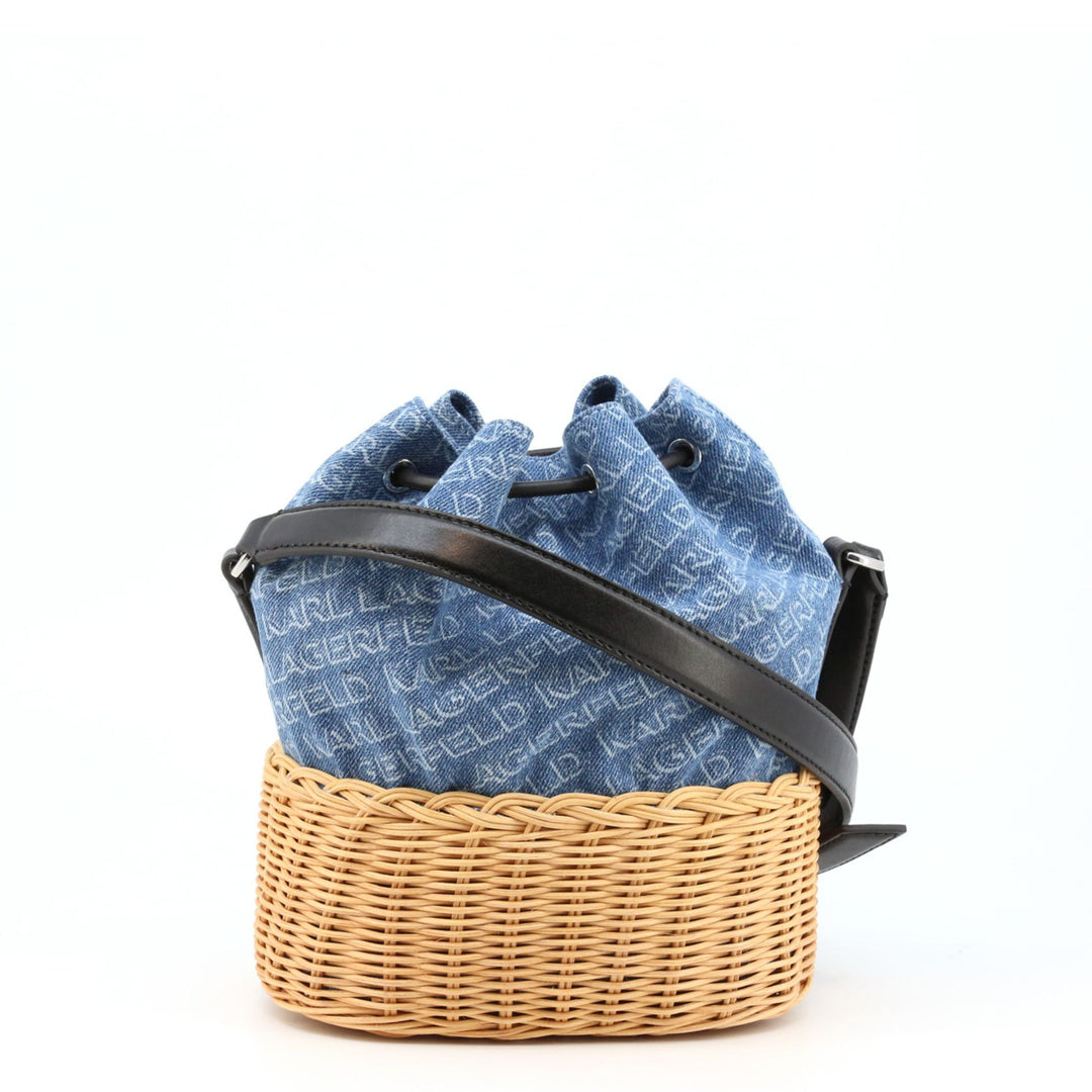 A blue Karl Lagerfeld crossbody bag with a black leather look, placed inside a wicker basket. The bag features a drawstring closure and an adjustable shoulder strap.