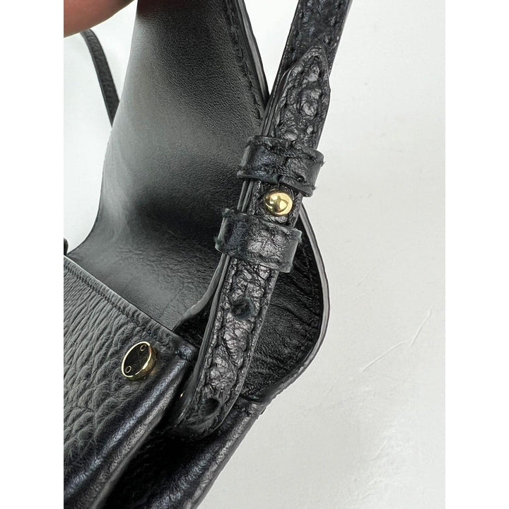 Close-up of a black leather handbag with gold hardware on a light gray background