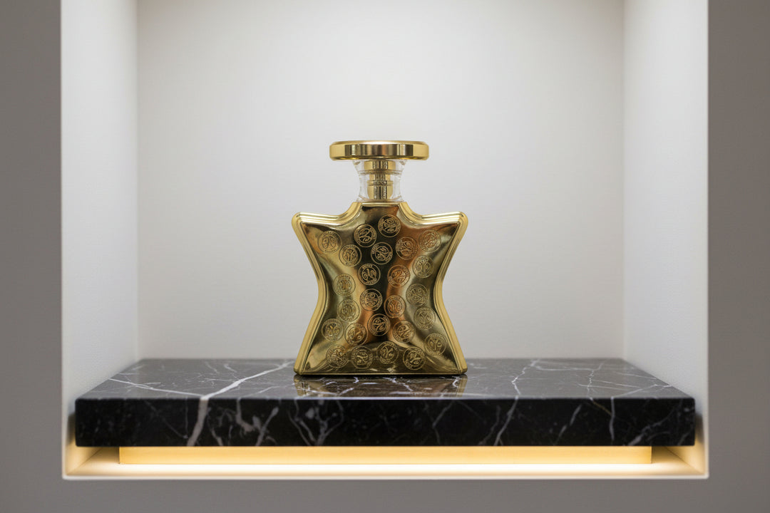 Gold perfume bottle with decorative logos on a white background