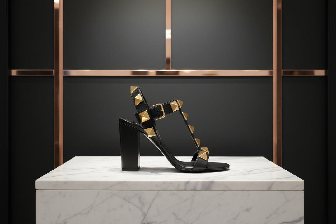 Black sandal with gold studs on a white background