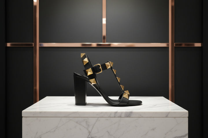 Black sandal with gold studs on a white background