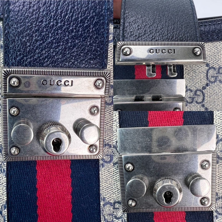 Close-up of the padlock and hardware on a Gucci GG Supreme Dollar Calfskin Web Small Padlock Navy Tote.