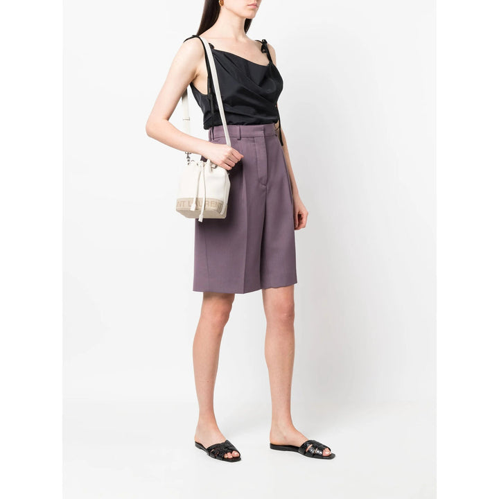 Woman wearing a black top and purple skirt with a white background