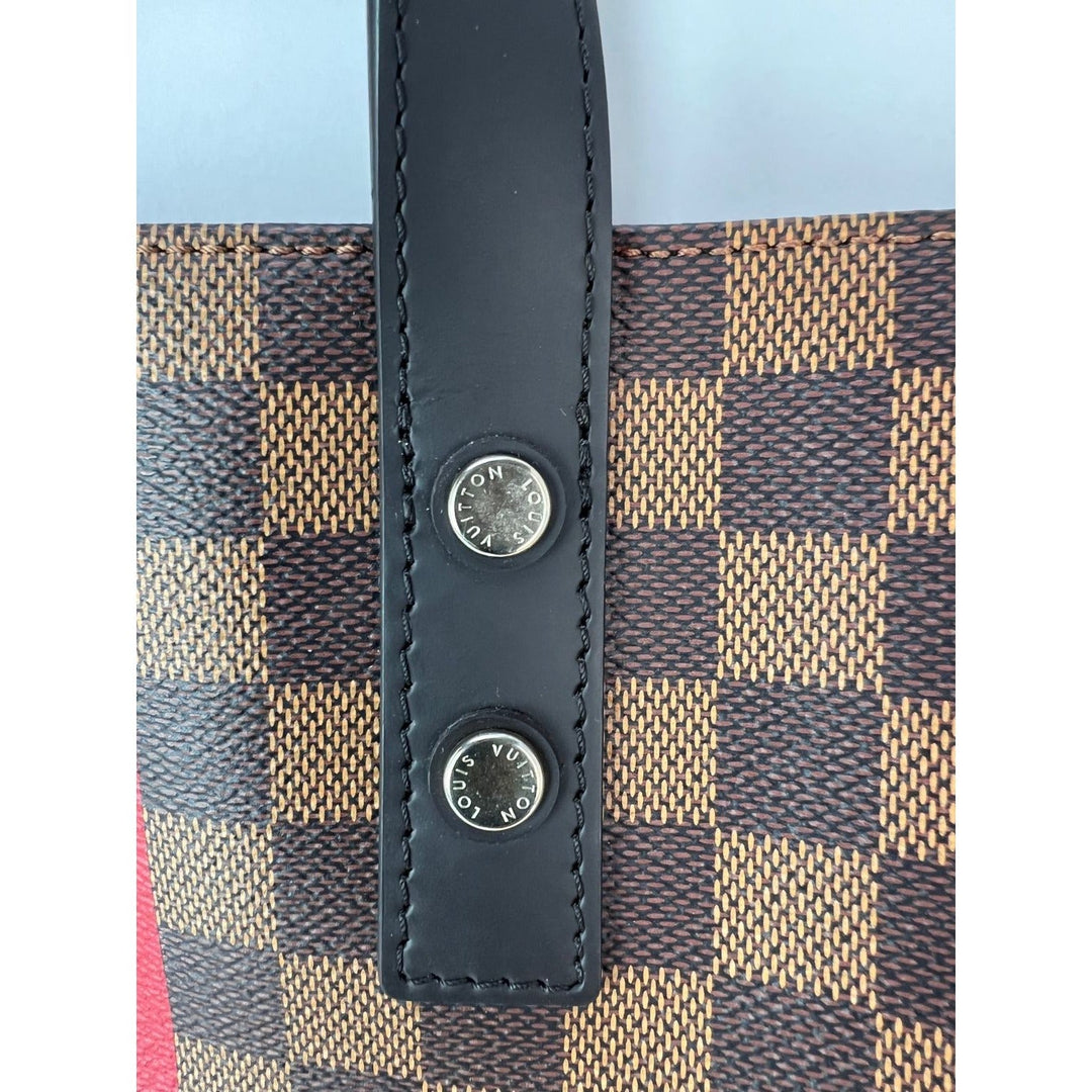 Close-up of a patterned fabric with black leather straps and Louis Vuitton logo.