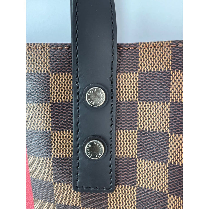 Close-up of a patterned fabric with black leather straps and Louis Vuitton logo.