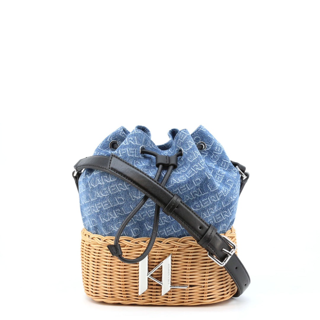 A blue Karl Lagerfeld crossbody bag with a black leather look, placed inside a wicker basket. The bag features a drawstring closure and an adjustable shoulder strap.