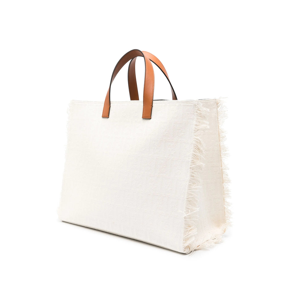 White tote bag with brown leather handles on a white background
