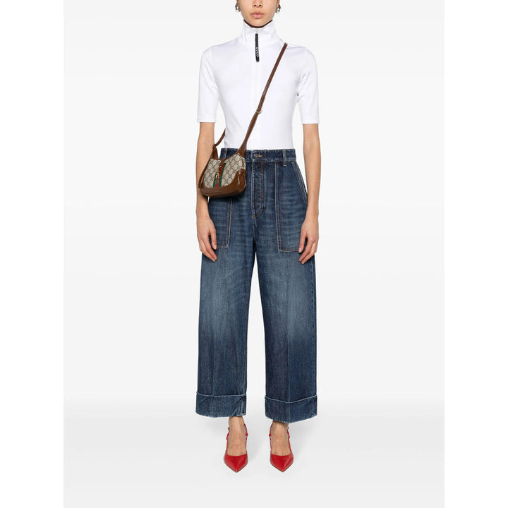 Person wearing a white top and blue jeans with a brown bag on a white background
