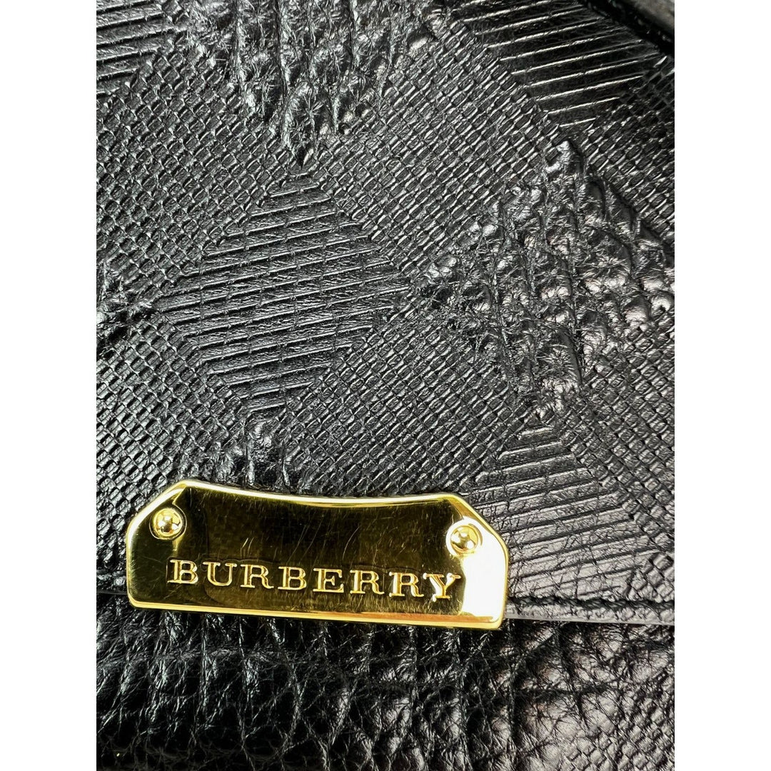 Burberry bag with gold tag on textured black leather background