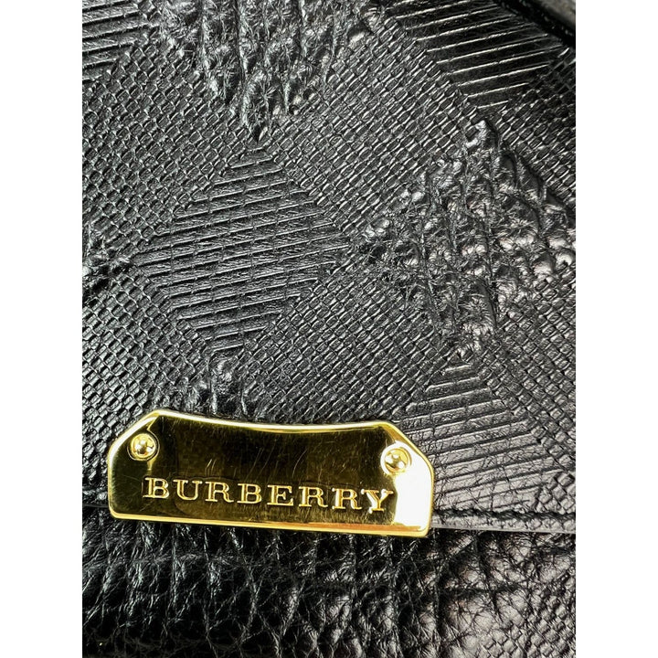 Burberry bag with gold tag on textured black leather background