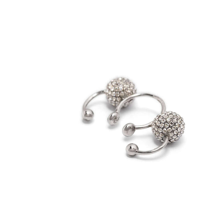 Silver ear cuff with embedded stones on a white background