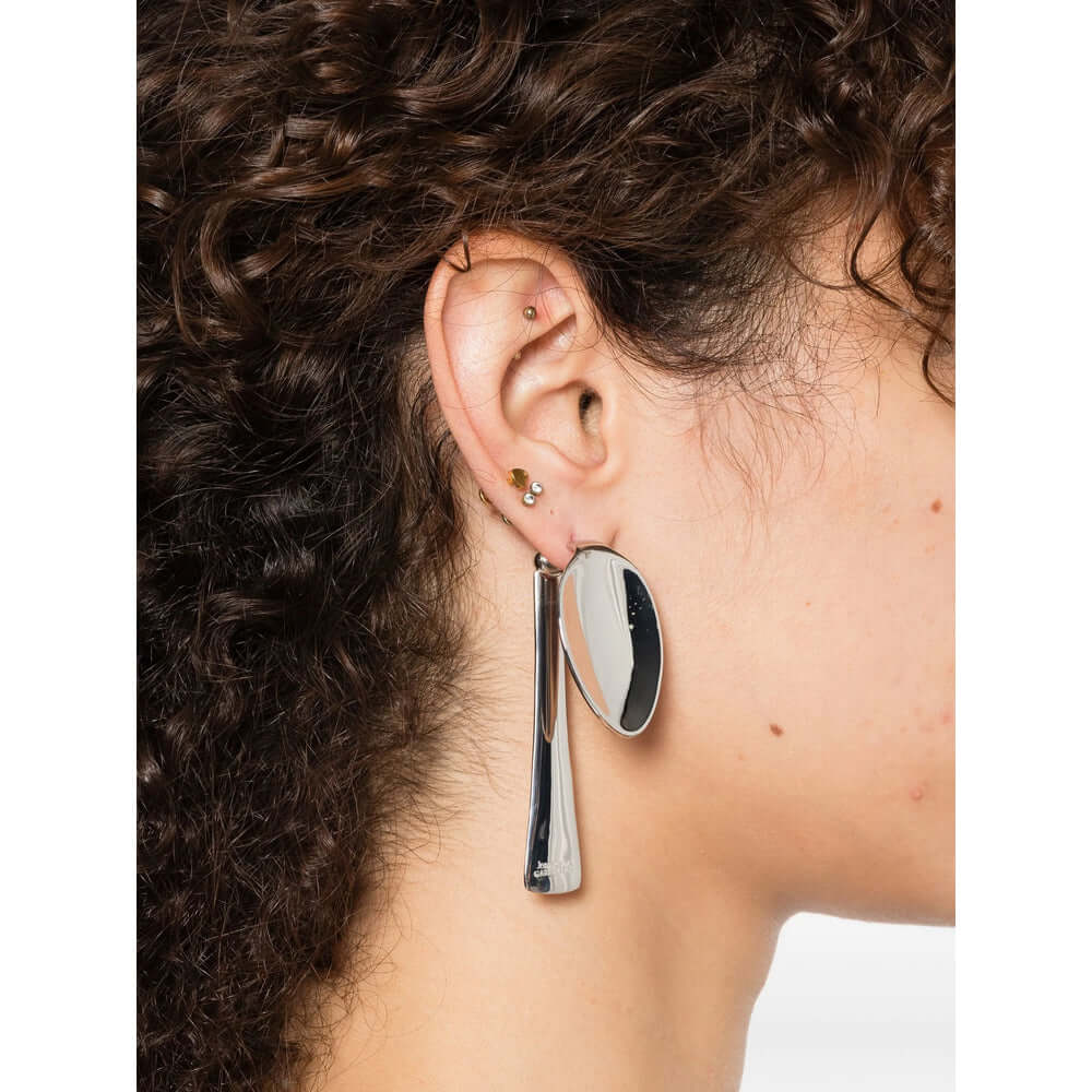 Close-up of an ear wearing a unique earring with a plain background