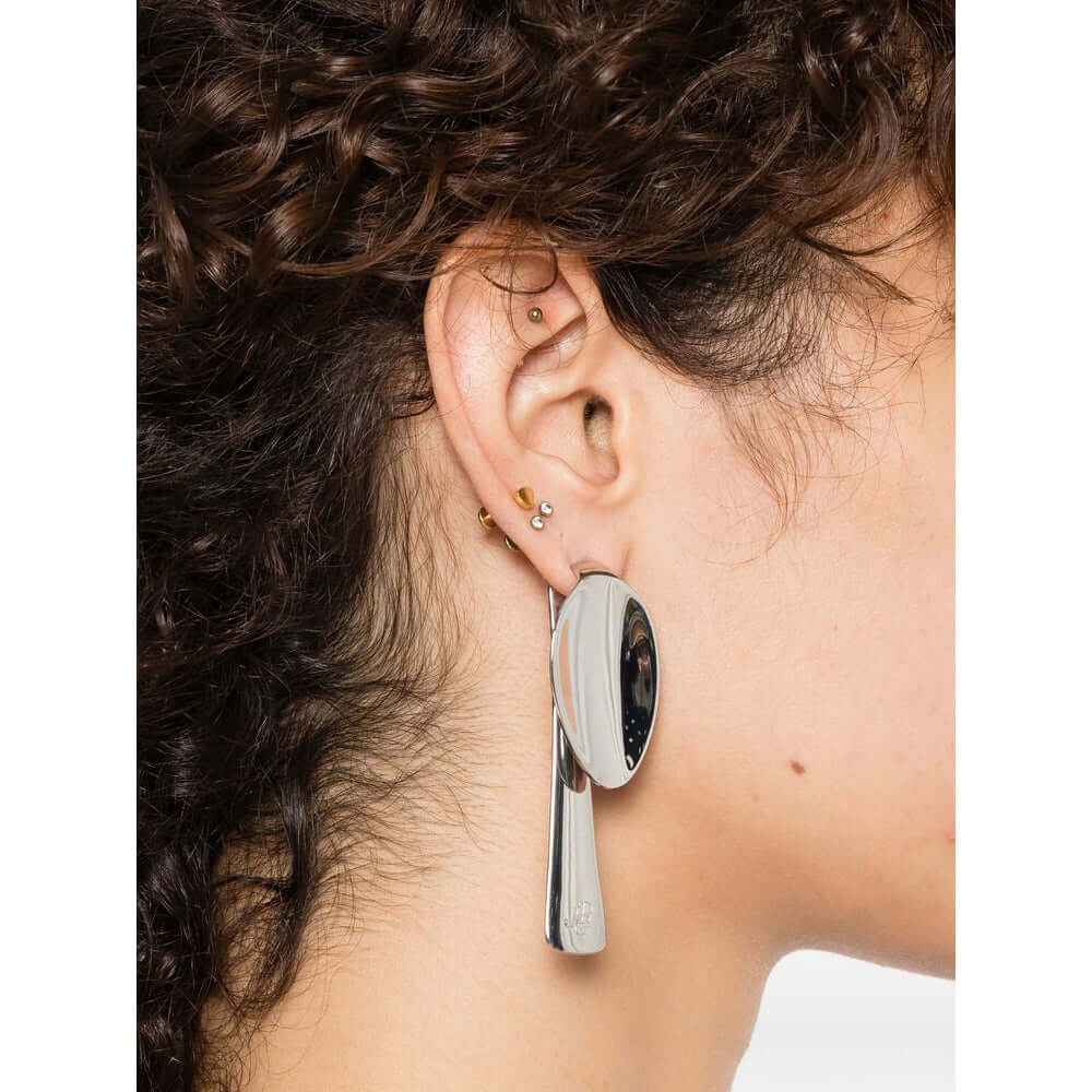 Close-up of an ear wearing a silver earring with a black stone.