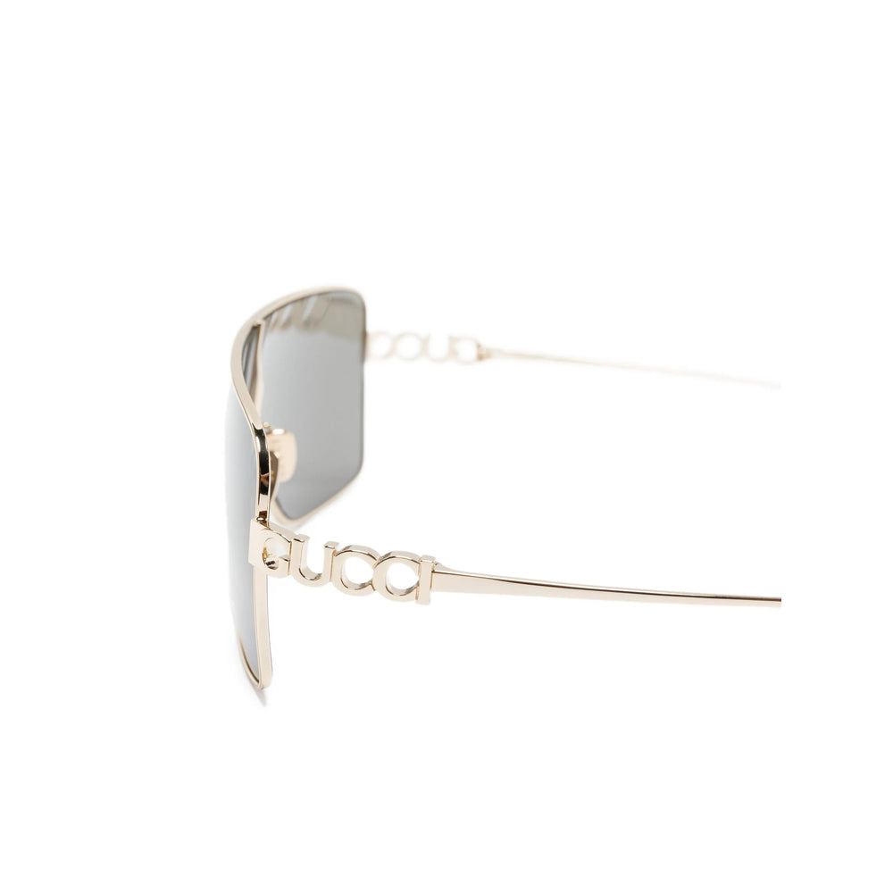 Gold-framed sunglasses with a clear lens on a white background
