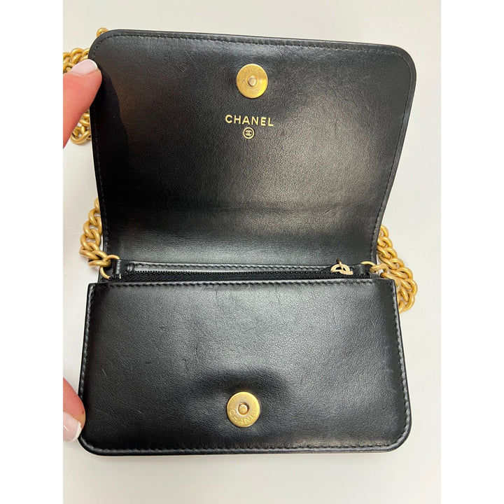 Chanel Caviar Quilted Mini Boy Clutch Wallet on a Chain Black interior showing gold hardware and logo.