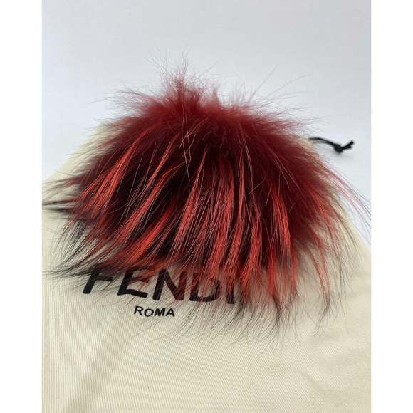 Red and black fur pom-pom on a Fendi bag with a white background
