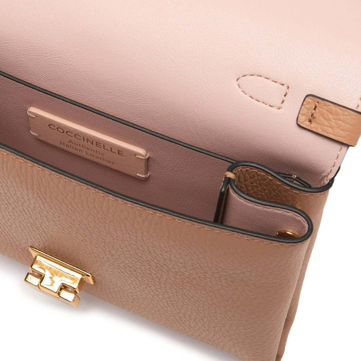 Close-up of a beige handbag with gold hardware and Coccinelle logo.