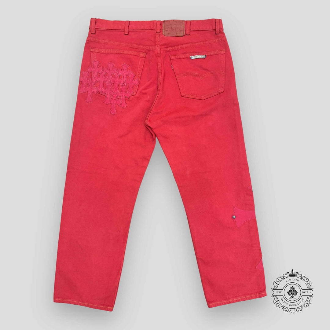 Red jeans with a heart design on the back pocket against a gray background