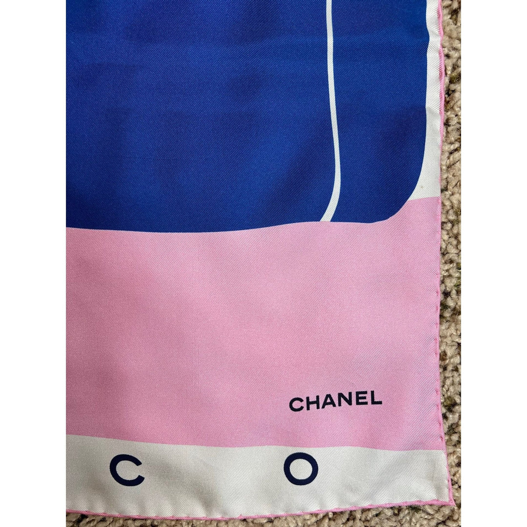 Chanel scarf with blue, pink, and beige colors on a carpeted floor.