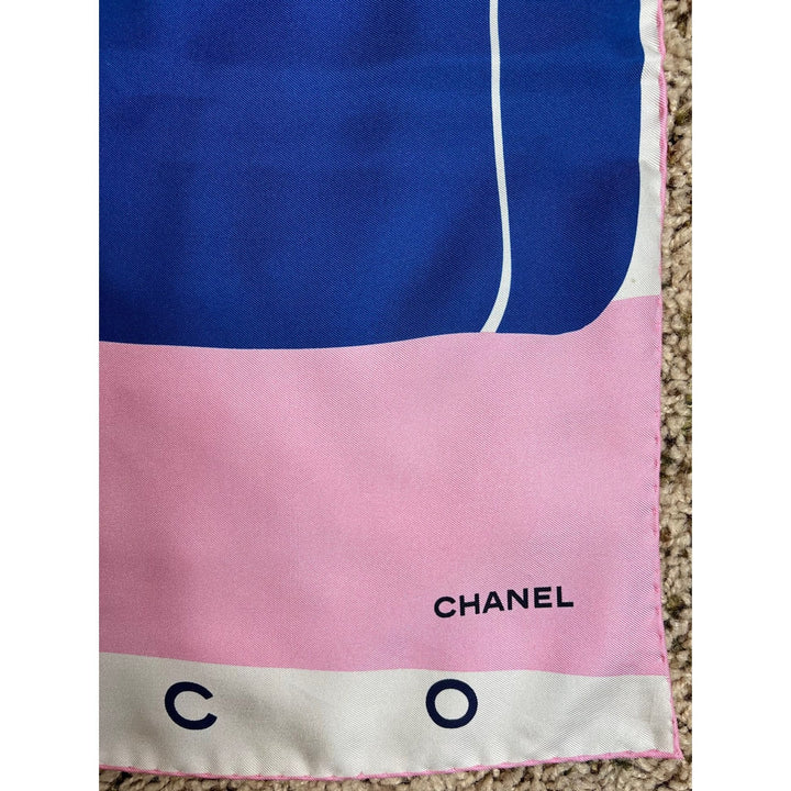 Chanel scarf with blue, pink, and beige colors on a carpeted floor.