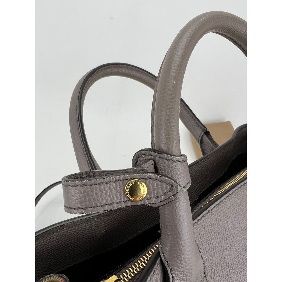 Close-up of a gray handbag with gold accents on a light gray background