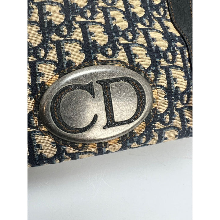 Close-up of the CD emblem on the CHRISTIAN DIOR Monogram Trotter CD Blue Canvas Hand Bag, showcasing luxury bags design details.