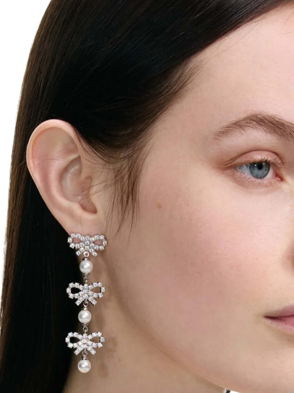 Close-up of a woman wearing elegant earrings with a neutral background