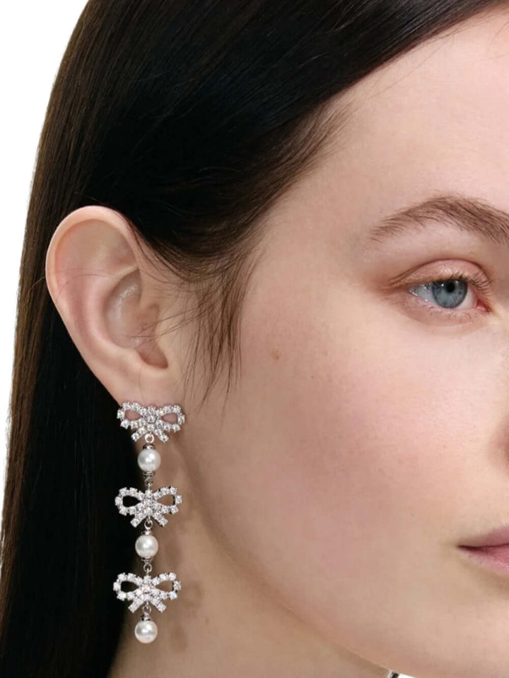Close-up of a woman wearing elegant earrings with a neutral background