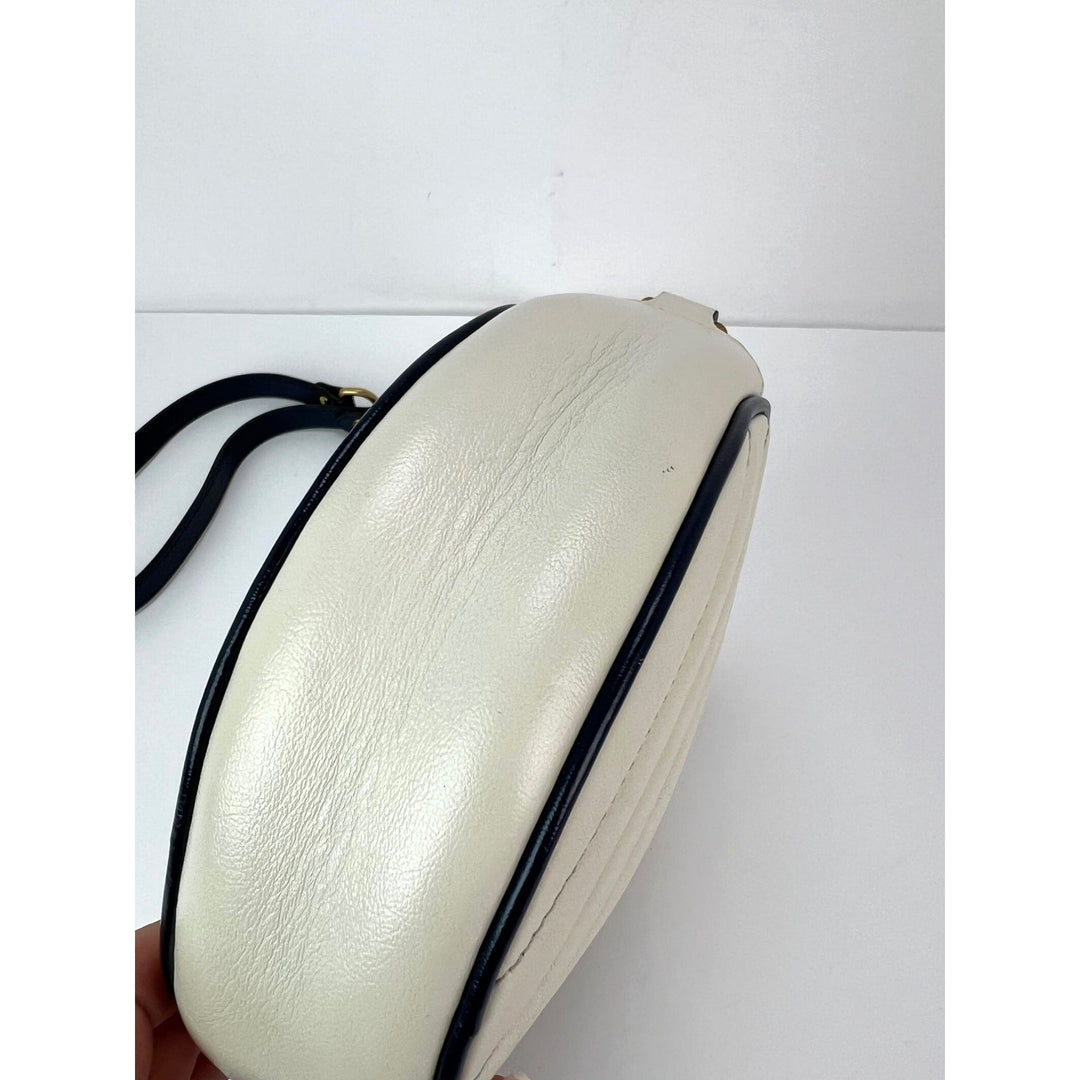 White handbag with black strap on a white background
