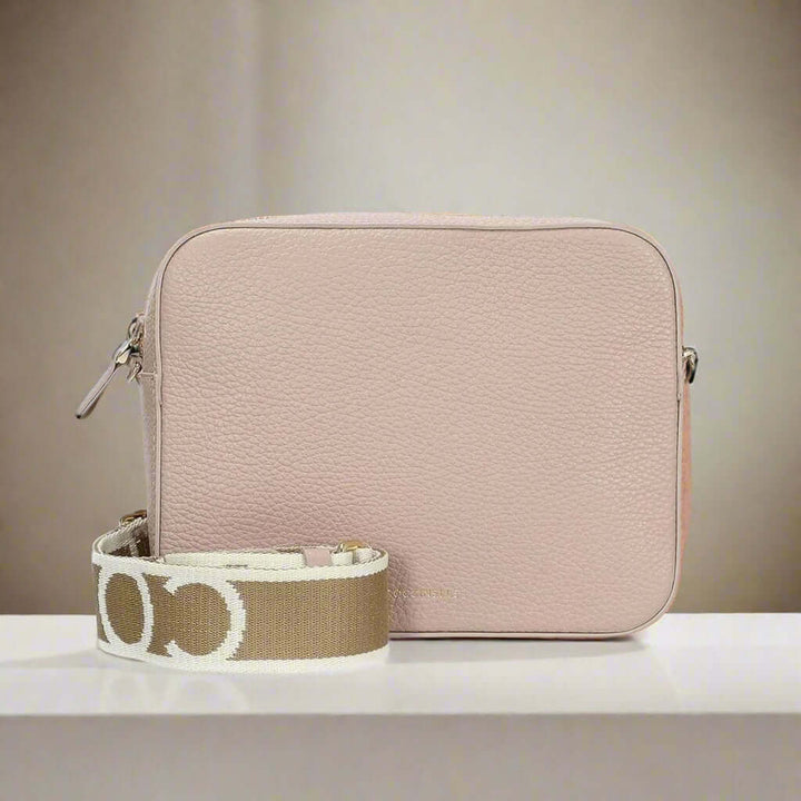 Pink crossbody bag with a brown strap featuring white patterns on a white background