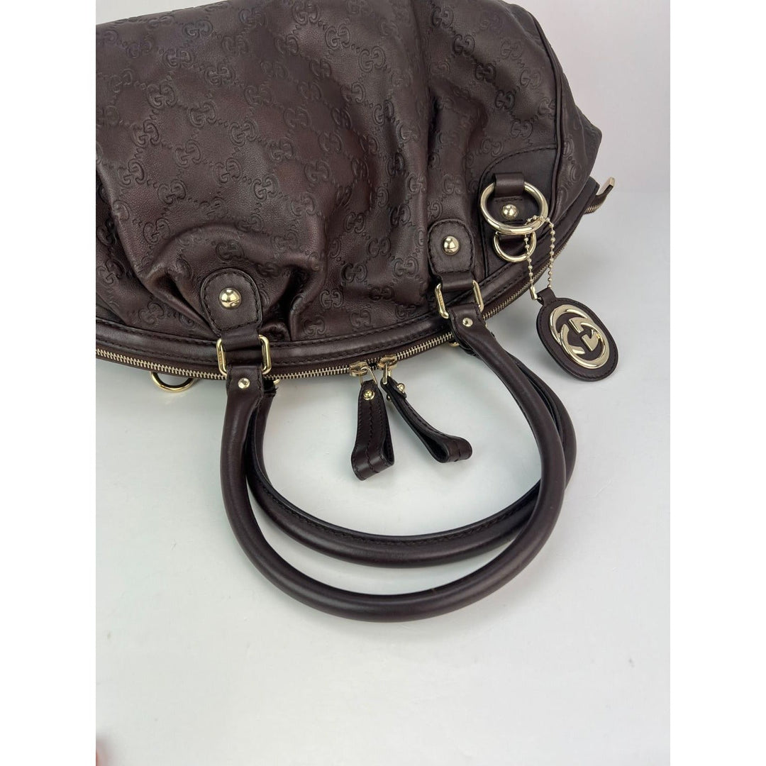 Brown handbag with gold hardware on a light gray background