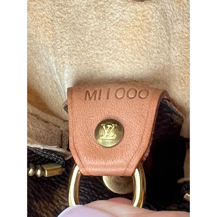 LOUIS VUITTON Looping GM Monogram Shoulder Bag tag showing MI1000 code and golden hardware, a symbol of luxury bags.