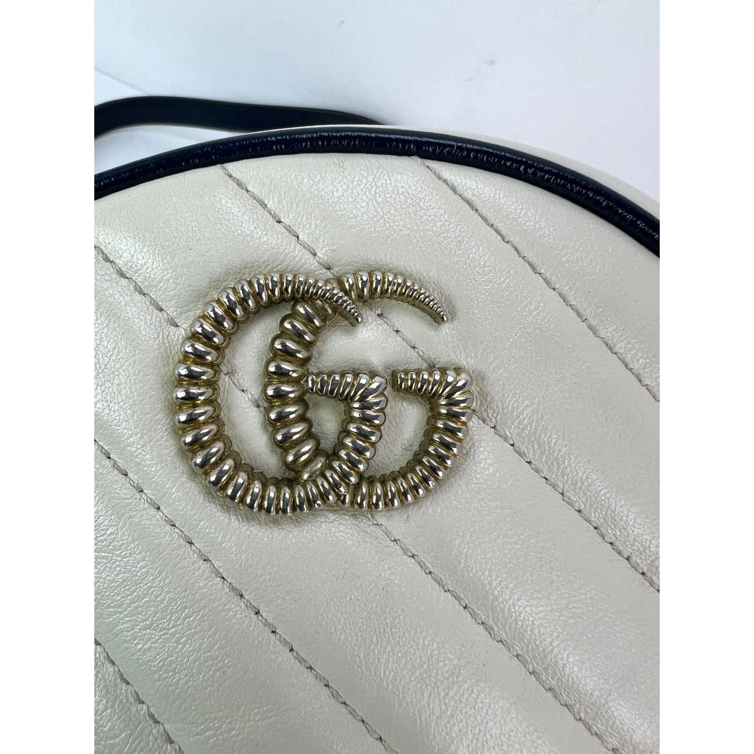 White quilted handbag with a decorative 'G' emblem on a white background