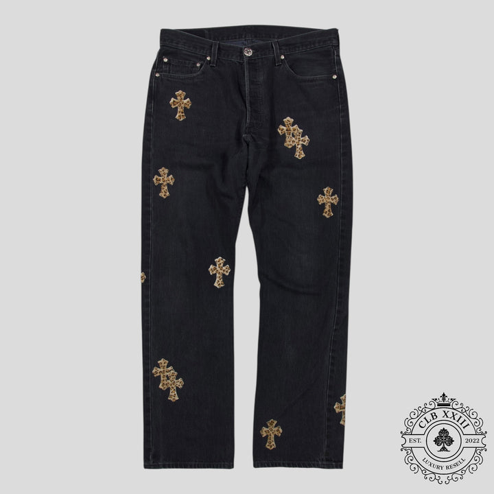 Black jeans with gold cross patterns on a gray background