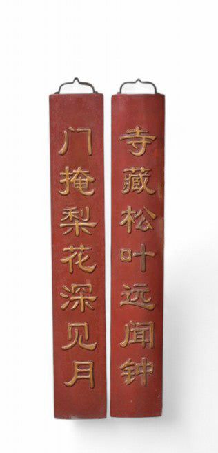 Pair of red wooden couplets with Chinese characters on a white background